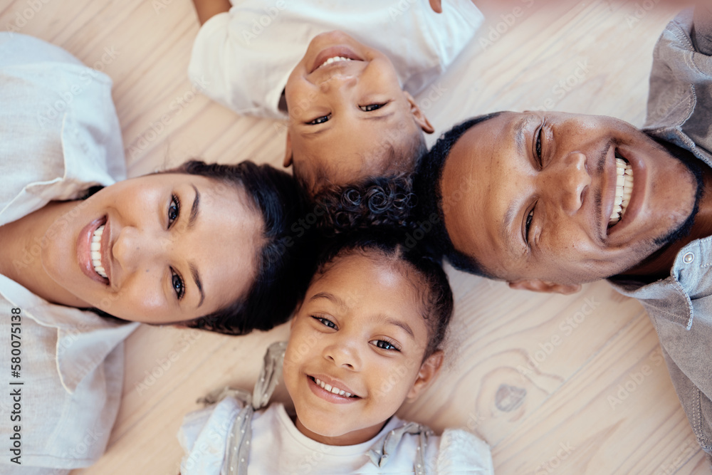 Happy, smile and portrait of family on floor with top view for bonding, support or relax in living room. Funny, playing and affection with face of parents and children on ground at home for happiness Happy, smile and portrait of family on floor with top view for bonding, support or relax in living room. Funny, playing and affection with face of parents and children on ground at home for happiness