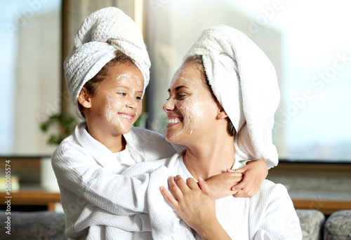 Happy  smiling and relaxed mother and daughter spa day at home with face masks for healthy skincare and personal hygiene. Cute little girl and parent bonding and enjoying a pamper treatment together