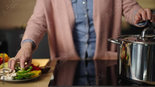 Close-up shot of an urecognized female chef blanching vegetables in a big cooking pot. Slow-motion shot photo