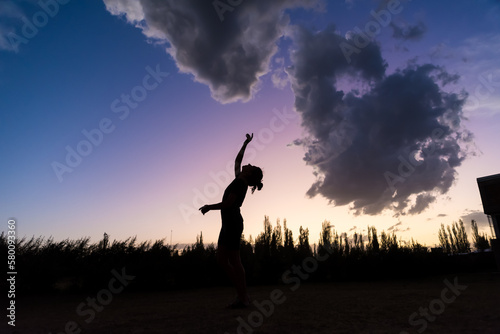 A woman in front of a sunset sky