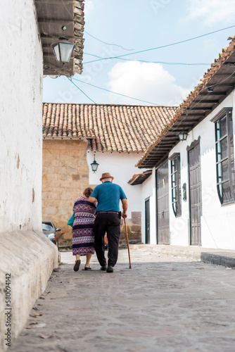 elderly couple walking through a town with cane on stone streets