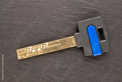 One metal door lock key on slate stone, macro, top view. © Oleksandr