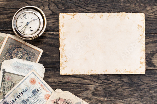 Old sheet of paper with obsolete european banknotes and vintage clock. Financial or numismatic concept