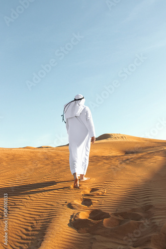 Arabian sheikh in long white dress closeup in the middle of Dubai desert.