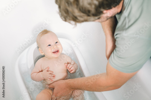 Cute newborn baby girl having fun while taking a bath. Father daughter time.