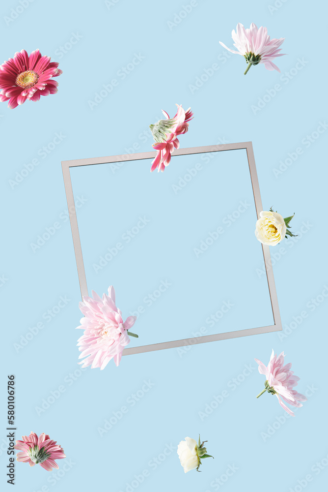 Obraz premium Colorful spring flowers flying with frame. Copy space for text on a blue background. Florist arrangement concept.