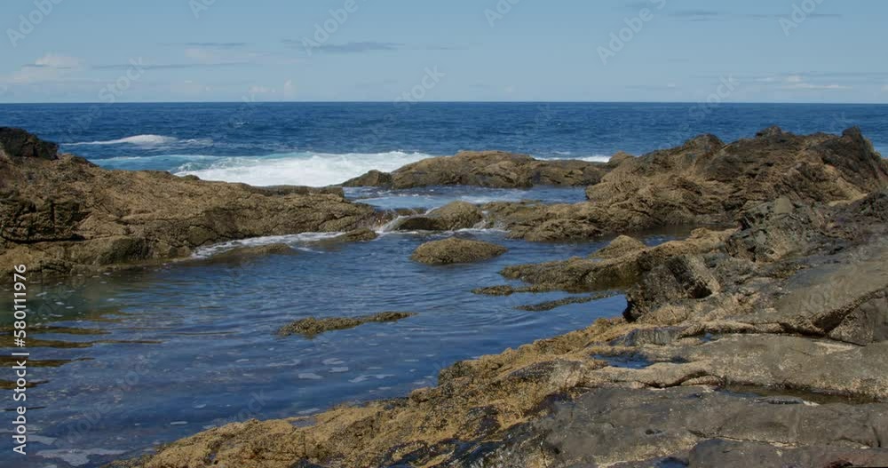 Powerful waves are crashing and foaming against black volcanic rocks on the coast of Fuerteventura island. Travel and vacation concept. Powerful waves are crashing and foaming against black volcanic rocks on the coast of Fuerteventura island. Travel and vacation concept.