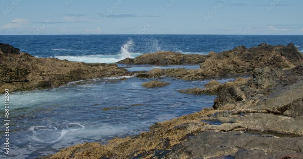 Powerful waves are crashing and foaming against black volcanic rocks on the coast of Fuerteventura island. Travel and vacation concept. Powerful waves are crashing and foaming against black volcanic rocks on the coast of Fuerteventura island. Travel and vacation concept.