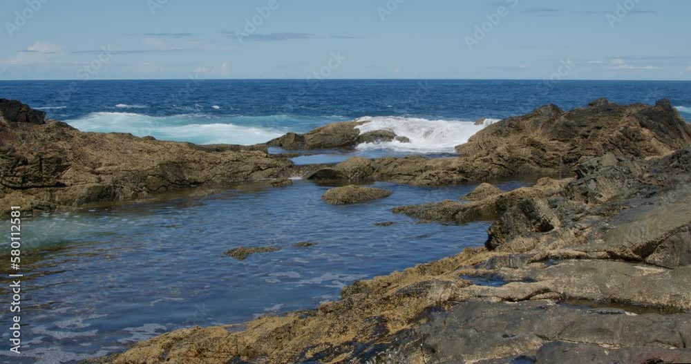 Powerful waves are crashing and foaming against black volcanic rocks on the coast of Fuerteventura island. Travel and vacation concept. Powerful waves are crashing and foaming against black volcanic rocks on the coast of Fuerteventura island. Travel and vacation concept.