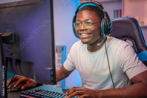 Portrait of young gamer playing online computer games with headphones streamer in colorful neon room