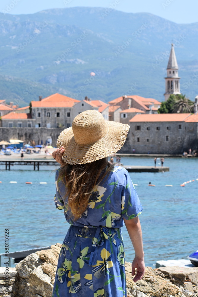 Woman at the beach watching the old town of Budva 