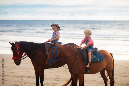 Kids riding horse on beach. Children ride horses.