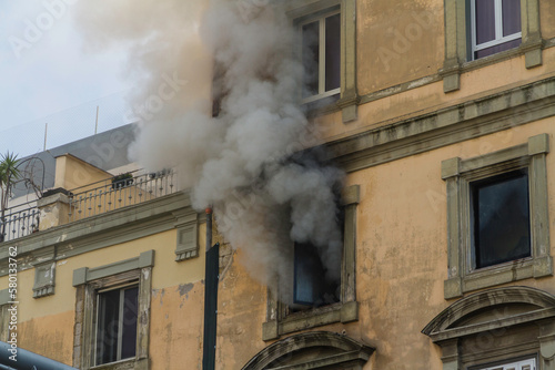 Domestic apartment fire with smoke billowing from window. Garibaldi Square, Naples, Italy