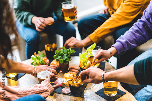 Group of happy friends eating food and drinking beer  at brewery pub restaurant- Young people enjoying happy hour with appetizer gourmet at bar table- Life Style Dining and   Beverage concept photo