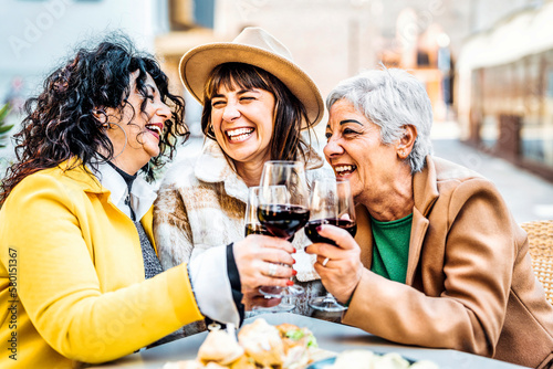 Three happy retired female drinking and toasting red wine glasses at bar restaurant - Group of happy elderly women having fun in the city - Concept about older friends smiling and laughing together