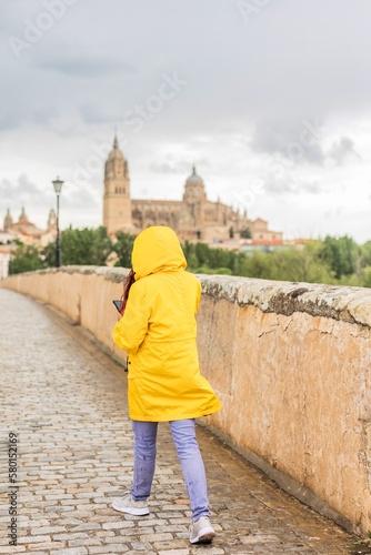 woman happy under raining with waterproof coat. Mid latin venezuelan in Salamanca Spain. unesco
