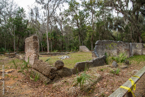 The crumbled walls of the Taby Ruins surrounded lush green trees, plants and grass with blue sky and clouds at Wormsloe Historic Site in Savannah Georgia USA photo