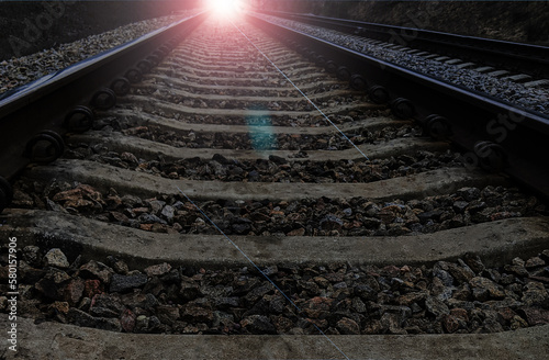 railway rails from a low shooting point go into a distant perspective, from which a bright light is directed towards the viewer