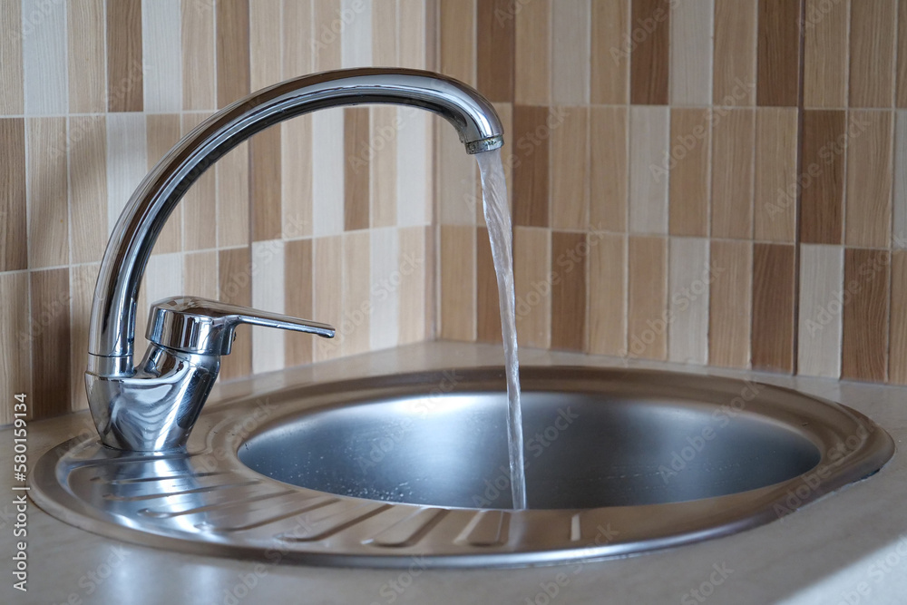 Water pours in a strong stream from the tap in kitchen Water pours in a strong stream from the tap in kitchen