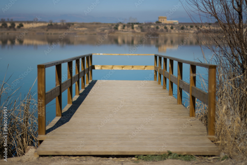Puente flotante sobre un lago que parece un espejo, donde se refleja todo el paisaje.