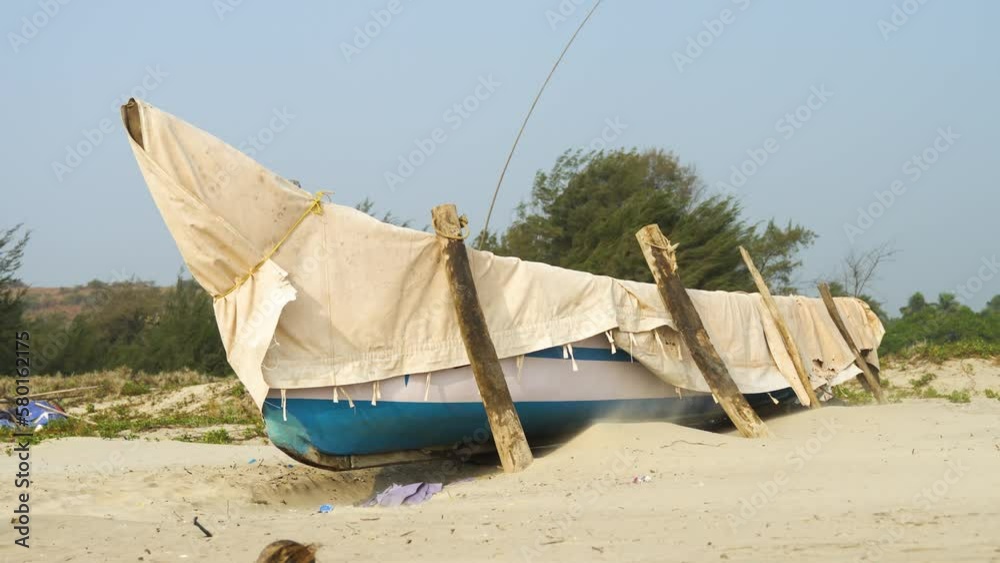 Old boat covered with an awning stands on the sandy shore of the beach Old boat covered with an awning stands on the sandy shore of the beach