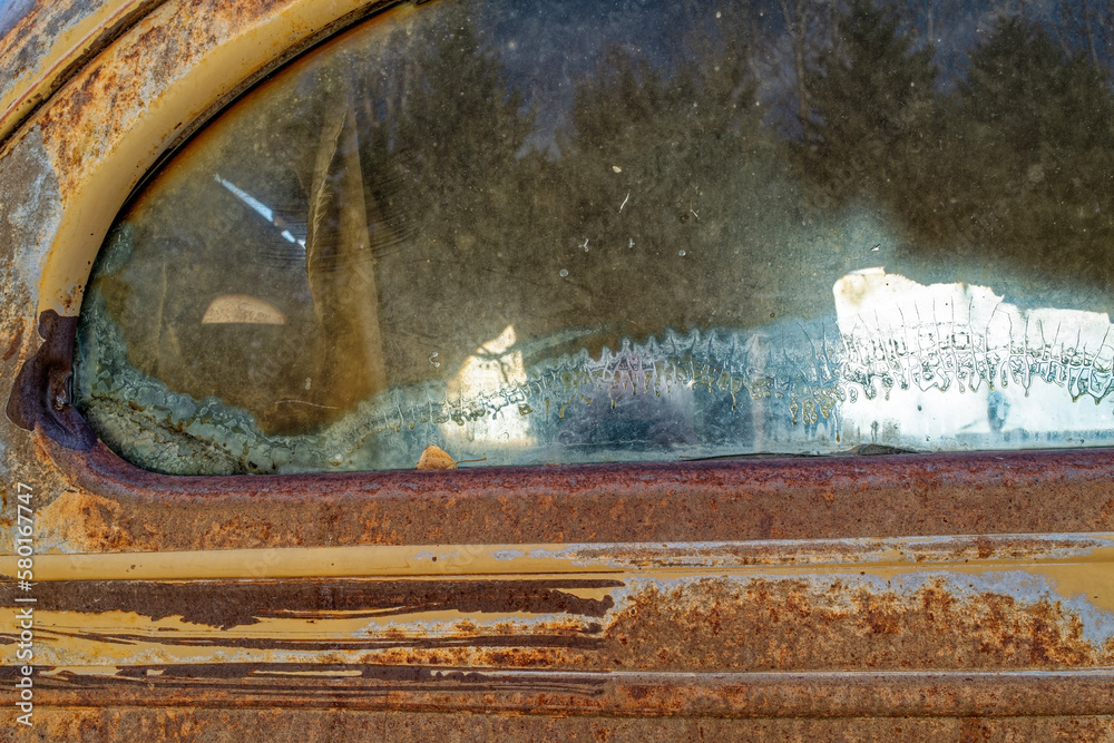 Patterns in the glass of the rear window of an antique rusty panel truck