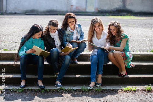 a group of female students sitting with books in the courtyard of the university