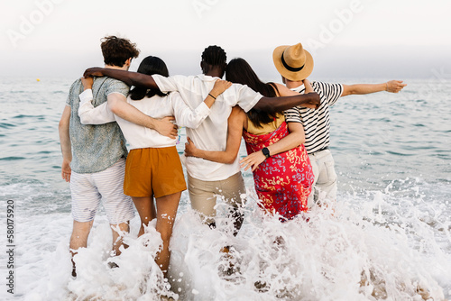 Foto View from back of group of young diverse people friends hugging each other and e