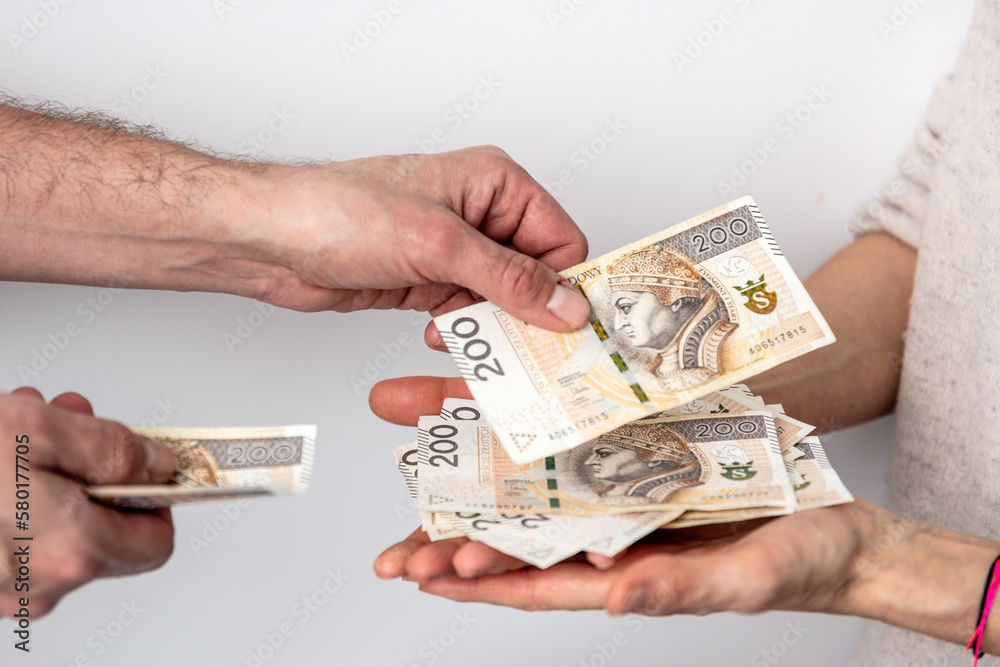Dłonie mężczyzny i kobiety wymieniających się pieniędzmi. Banknoty na białym tle. Liczenie pieniędzy. - obrazy, fototapety, plakaty 