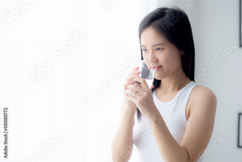 Beautiful young asian woman drinking glass of water mineral pure with fresh and happy at home, asia female drinking beverage for healthcare and weightloss, one person, lifestyles concept.