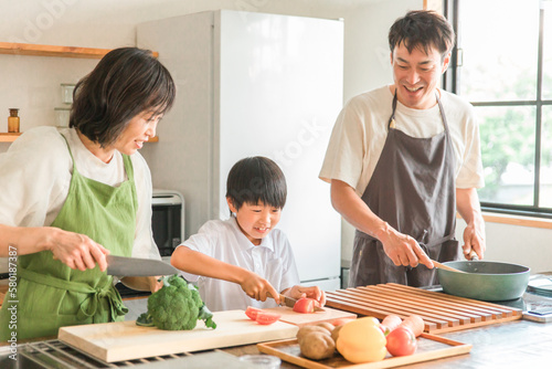 家のキッチンで子供と一緒に料理・クッキングする夫婦・親子・家族・男女
