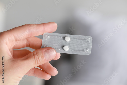 Woman holding blister of emergency contraception pills on white background, closeup