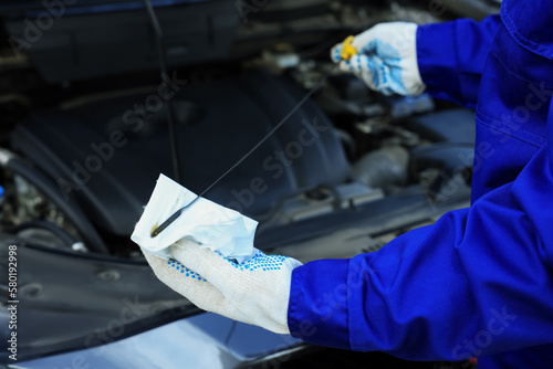 Worker checking motor oil level in car with dipstick, closeup