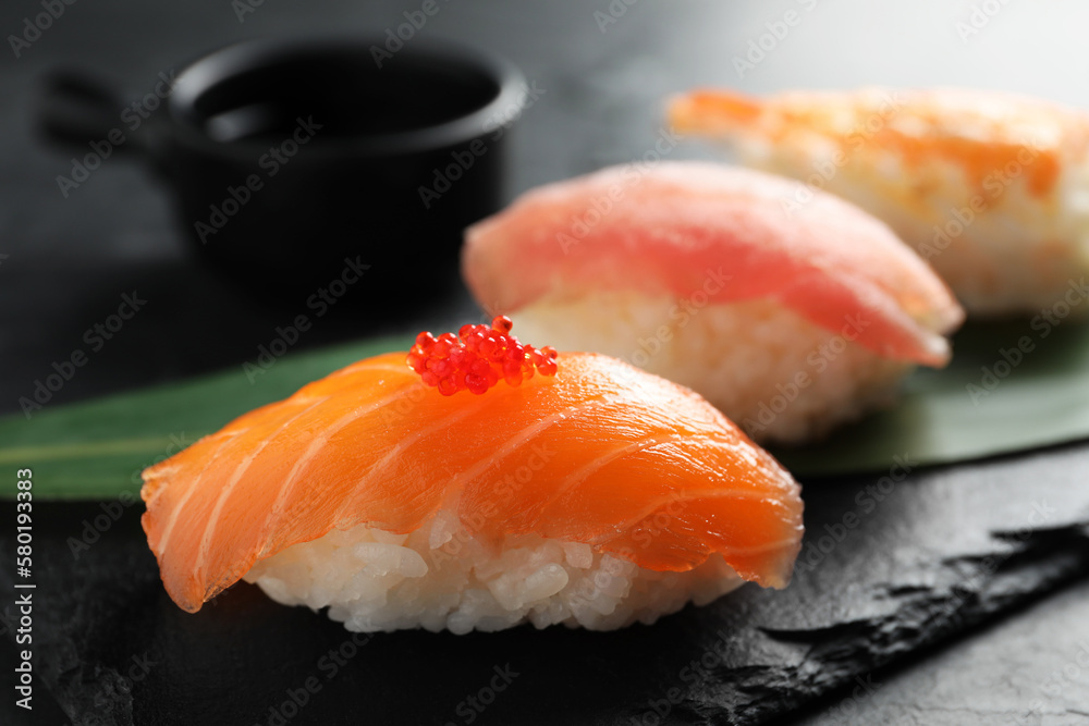 Serving board with delicious nigiri sushi and soy sauce on black table, closeup Serving board with delicious nigiri sushi and soy sauce on black table, closeup