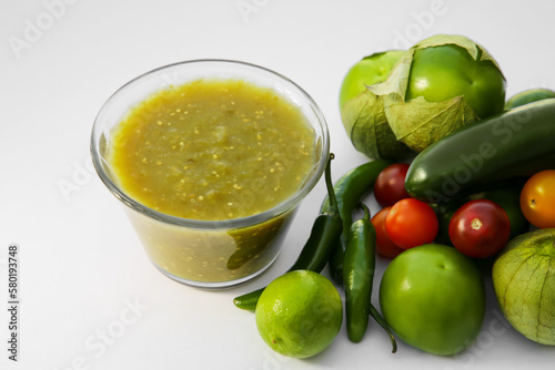 Bowl with delicious salsa sauce and ingredients on white background, closeup