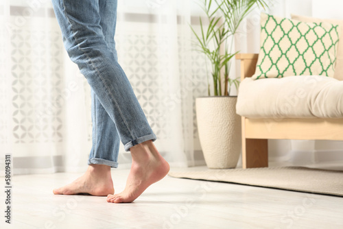 Barefoot man walking on white parquet at home, closeup. Heated floor