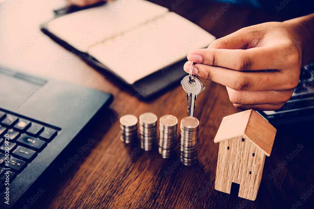 Hand choose house key with coins stack in graph shape for real estate or money savings planning