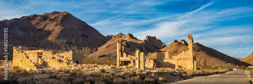 Ghost town stone ruins of an old building in a mountainous desert landscape on a clear day.