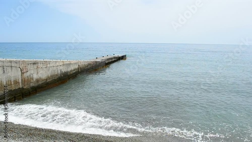 stone barrier protection against waves (long concrete  barricade wall construction), blue ocean, blue sky in sunny day, summer environment diversity