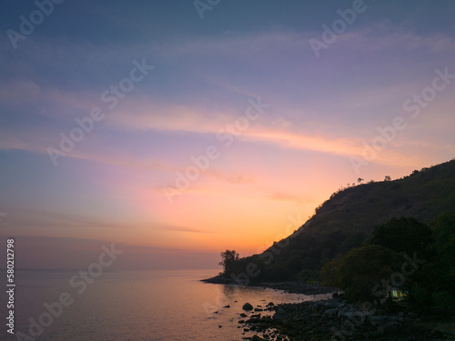 aerial view the sun going down in colorful sky impact on ocean surface.The beauty of the cliff fits perfectly with the charming nature in beautiful sunset..cloud scape background © Narong Niemhom