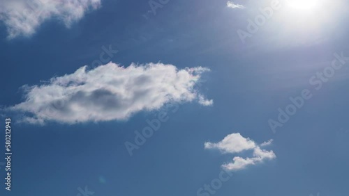 a pan from the sky to a green field. bright blue sky with sun and a plane flies past.