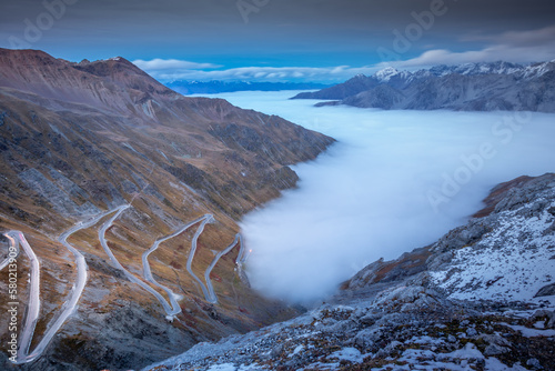 Stelvio pass, mountain road dramatic landscape at dawn above mist, Italy