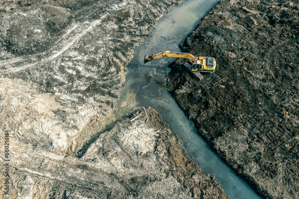 big powerful excavator digging drainage ditch in swampy countryside. birds eyes view. big powerful excavator digging drainage ditch in swampy countryside. birds eyes view.