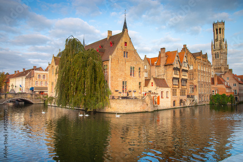 Architecture of idyllic Bruges with canal and swans floating in a row, Flanders, Belgium