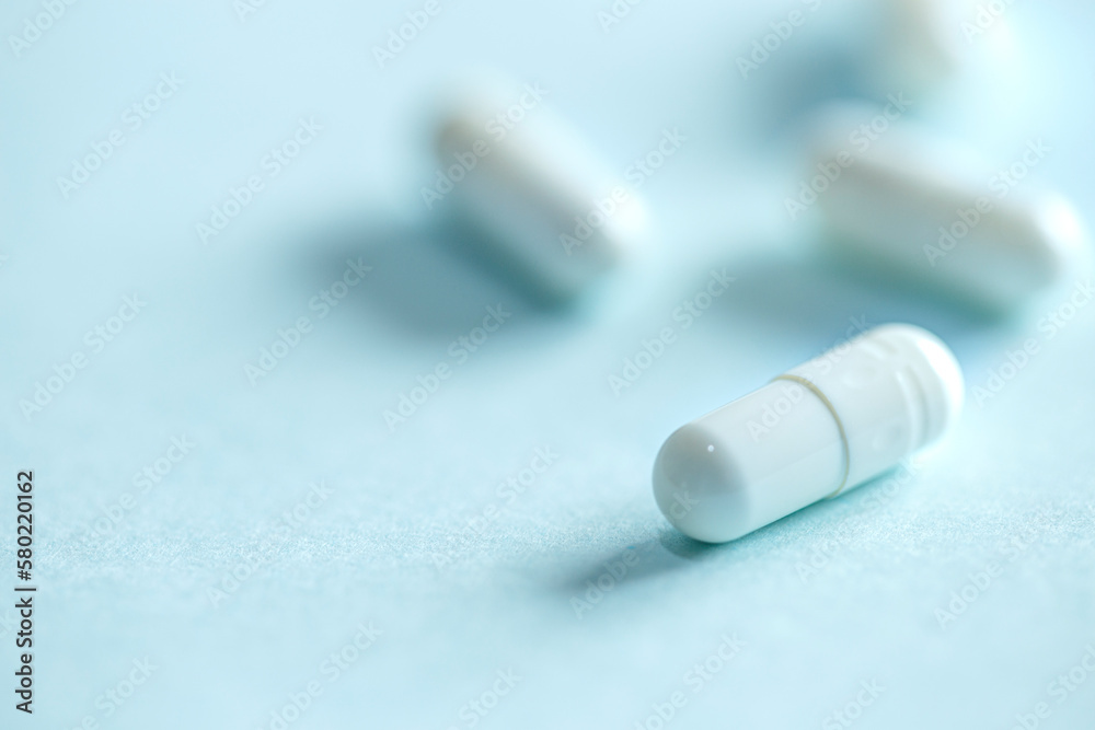White capsule pill on blue background White capsule pill on blue background