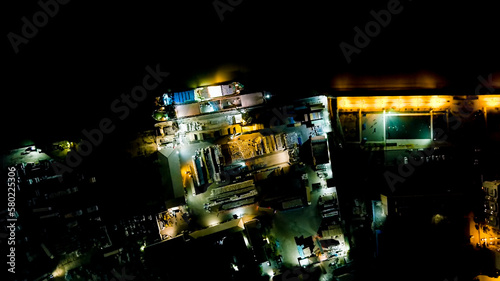 Fototapeta Naklejka Na Ścianę i Meble -  Astrakhan, Russia. Port cranes unload dry cargo. Working port. Embankment of the Volga River. Night city lights, Aerial View