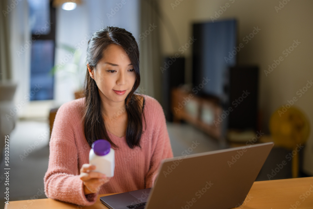 Woman check the ingredient of the medicine on laptop computer Woman check the ingredient of the medicine on laptop computer