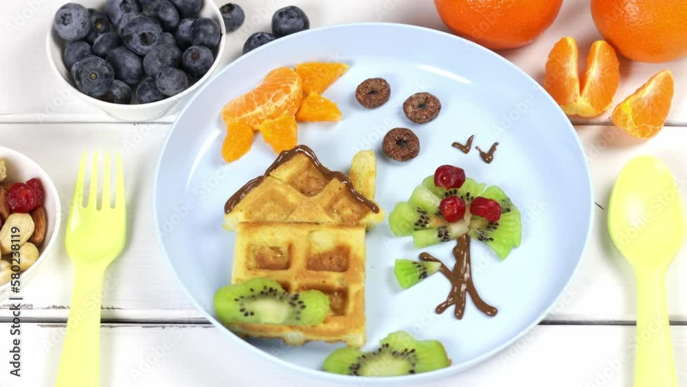 Children's breakfast: waffles and fruits on a blue plate. A creative idea for a fun kids dessert or breakfast