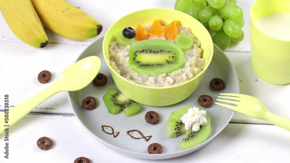Serving children's cheerful breakfast of oatmeal with fruits in the form of a funny muzzle of a frog Serving children's cheerful breakfast of oatmeal with fruits in the form of a funny muzzle of a frog