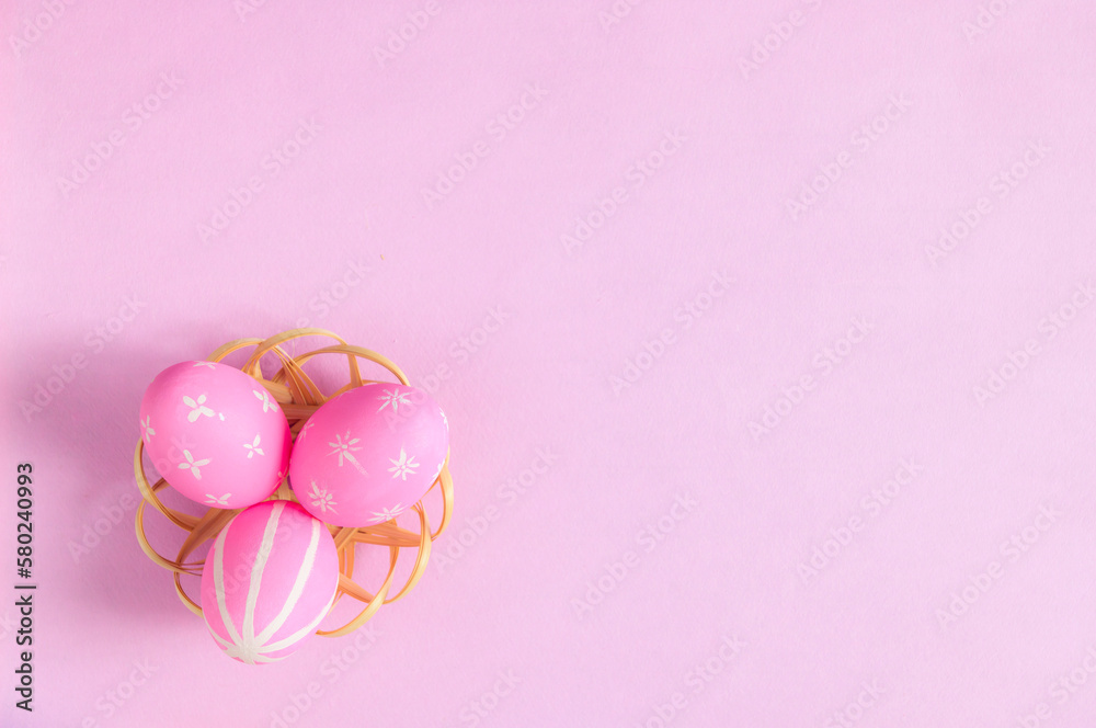 Happy Easter holiday greeting card concept. Colorful Easter Eggs and spring flowers on pastel pink background. Flat lay, top view, copy space.